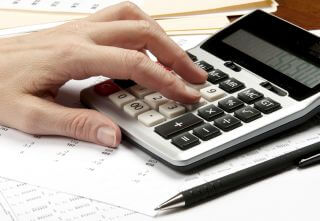 Hands on calculator with pen and financial papers